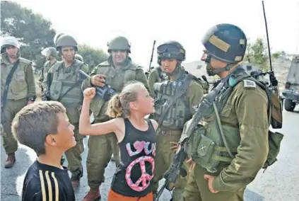  ??  ?? ► Ahed Tamimi, entonces de 12 años, trata de golpear a un soldado israelí en Nabi Saleh en 2012.