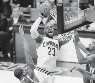  ??  ?? Cavaliers forward LeBron James shoots between Warriors forwards Andre Iguodala, left, and Kevin Durant during the second half of Game 4 in Cleveland.