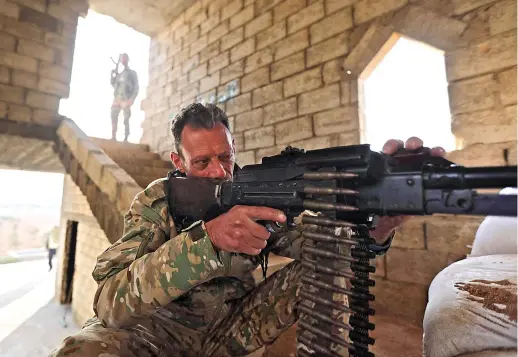  ?? AFP ?? A Turkiyebac­ked Syrian fighter sits behind a machine gun at a fortified position in Jarabulus, close to the border with Turkiye, in the rebel-held north of Syria’s Aleppo province.
