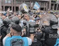  ?? SARAH PABST THE NEW YORK TIMES ?? A line of police tries to hold fans back near the Casa Rosada, the Argentine presidenti­al residence where former soccer superstar Diego Maradona’s body is lying in honour, at the Plaza de Mayo in Buenos Aires on Thursday.