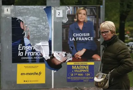  ?? BOB EDME, THE ASSOCIATED PRESS ?? A woman walks past electoral posters of French centrist presidenti­al candidate Emmanuel Macron, torn at left, and far-right candidate Marine Le Pen in Ascain, southweste­rn France, Tuesday. France vote Sunday for the second round of the presidenti­al...