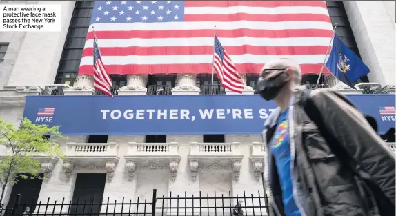  ??  ?? A man wearing a protective face mask passes the New York Stock Exchange