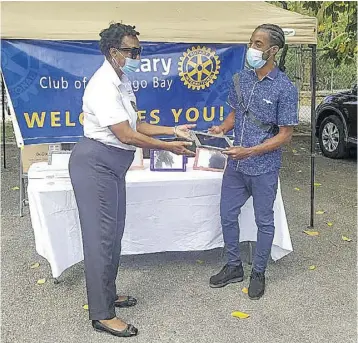  ??  ?? Rotarian Valerie Lewis O’bryan (left) presents a tablet to HEART/NSTA Trust student Tadain Evans during the handing over ceremony at The Salvation Army Divisional Headquarte­rs in West Green, Montego Bay, last week.