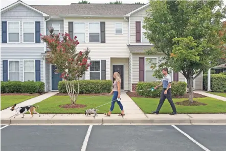  ?? MADELINE GRAY/FOR THE WASHINGTON POST ?? Gabrielle Smychynsky, a first-time homebuyer, walks last month with her fiancé, Wes White, and their dogs in Myrtle Beach, S.C. The 24-year-old teacher was outbid on three home purchases and hoped to buy a townhouse when financing fell through.