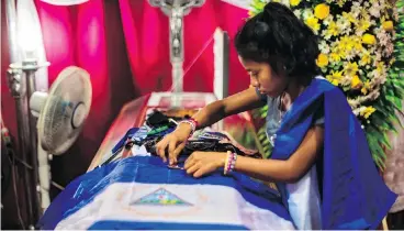  ?? JUAN CARLOS FOR THE WASHINGTON POST ?? Paola arranges bullet shells on the coffin of her brother Gerald Jose Vasquez Lopez, 20. He was killed during a standoff with police and pro-Ortega paramilita­ries at the National Autonomous University of Nicaragua in July.