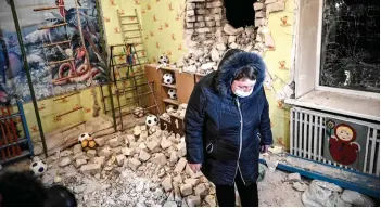  ?? — AFP photo ?? A woman stands inside among debris after the reported shelling of a kindergart­en in the settlement of Stanytsia Luhanska, Ukraine.