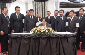  ?? ELIAH LILLIS ?? Leng Peng Long, general secretary of the National Assembly, writes a message of condolence in a book yesterday at Phnom Penh’s Wat Than pagoda.