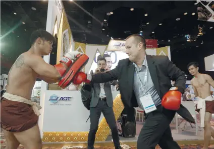  ?? SUNSTAR FOTOS / ALEX BADAYOS (ABOIVE), ARNI ACLAO (BELOW) ?? TIME FOR A BREAK. A delegate of the Routes Asia 2019 (above) tries his hand at Muay Thai at the Airports of Thailand booth. For others, the St. Ali coffee being served by the Melbourne Airport booth (below) is a welcome sight .