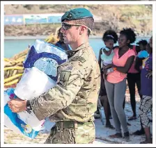  ??  ?? HELPING HAND: One soldier carries in supplies