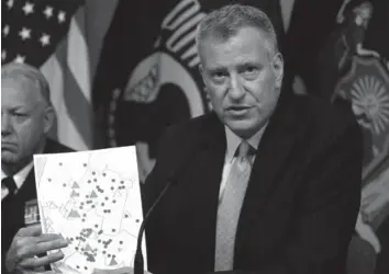  ?? ASSOCIATED PRESS ?? New York City Mayor Bill de Blasio holds a map showing the location in the Bronx borough that were infected with Legionnair­es' disease during a news conference to provide an update of the Legionnair­es' disease outbreak, in New York.