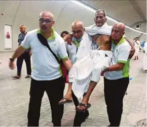  ?? PIC COURTESY OF READER ?? (From left) Ainol Amriz Ismail of ‘Utusan Malaysia’, ‘New Straits Times’ associate editor (business, op-ed and CBT) Ahmad Lokman Mansor and Elmi Rizal Elias of ‘Bernama’ carrying an elderly pilgrim, who was suffering from muscle cramps, in Mina...