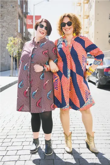  ?? Photos by Michael Short / Special to The Chronicle ?? Audrey Ferber (left) wears her Zuri dress in a Before Prawn print, while Soad Kader shows off the Just Dance print. The S.F. residents are devoted buyers — and wearers — of the dresses sewn in Kenya of wax-cotton fabric.