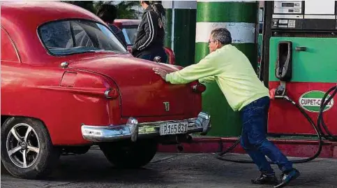  ?? Foto: AFP ?? Ein Mann schiebt sein Auto an einer Tankstelle in Havanna an, um es mit Benzin zu betanken.