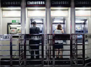  ?? PHOTO: BLOOMBERG ?? People use ATMs at an Industrial and Commercial Bank of China. Friday’s move, which cut one-year benchmark lending rates by 40 basis points to 5.6 percent arose from concerns that local government­s are struggling to manage high debt burdens.