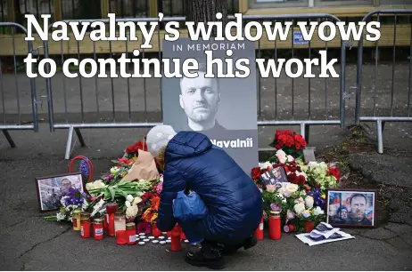  ?? Photos — AFP ?? A woman kneels at a makeshift memorial of flowers and candles for Kremlin critic Alexei Navalny at the Russian embassy in Bucharest, Romania.