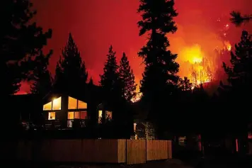  ?? The Associated Press ?? ■ The Caldor Fire burns near homes Wednesday near South Lake Tahoe, Calif.