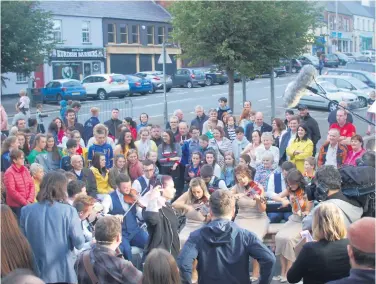  ??  ?? Crowds enjoying live street performanc­es during last year’s Ulster Fleadh in Castlewell­an (above), while young musician Cain Maginn plays the harp