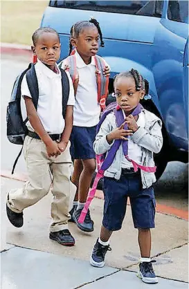  ??  ?? Chyna Garcia, 4, front, Zaybion Black, 4, and Serenity Williams, 6, walk up to the front door at the beginning of the first day of school Tuesday at Thelma Parks Elementary School in Oklahoma City.
