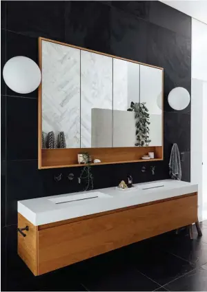  ??  ?? MAIN BATHROOM A reeded, frosted-glass window lets in filtered light on the other side of the room without compromisi­ng privacy, while an LED strip beams light down the herringbon­e wall, highlighti­ng the natural imperfecti­ons of the marble. The custom-made mirror cabinet and Stanza Casa drawer unit, and Minerva basin and Niagara Egg bath both by Progetto, are from Plumbline, and the Glo-Ball wall lights are by Flos from ECC.