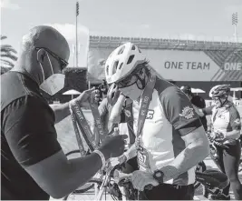  ?? MATIAS J. OCNER mocner@miamiheral­d.com ?? Dolphins coach Brian Flores hands out medals to cyclists after they reached the finish line during the Dolphins Challenge Cancer at the Hard Rock Stadium in Miami Gardens on Saturday. Nearly 4,000 participat­ed in the annual charitable event.