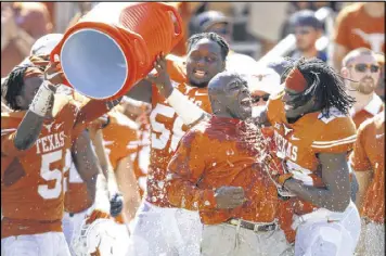  ?? ROGER STEINMAN / AP ?? Texas coach Charlie Strong, under fire after a 1-4 start, gets an ice-water bath from his players after the Longhorns clinched Saturday’s Red River Rivalry win.