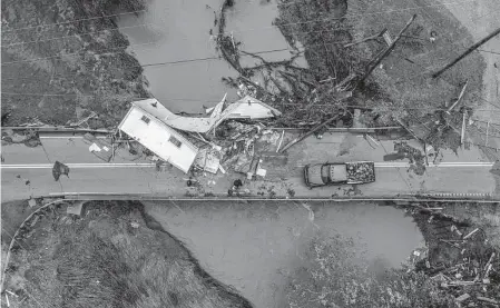  ?? Ryan C. Hermens/Associated Press ?? People work to clear a house from a bridge near the Whitesburg Recycling Center in Letcher County, Ky., on Friday. Record flash flooding has prompted a frantic search for survivors in entirely swamped towns.