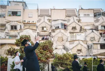  ?? ( Yonatan Sindel/ Flash90) ?? MEN PRAY outside the Ramot Polin Apartments in Jerusalem’s Ramot neighborho­od last month.