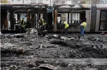  ?? ?? Debris is cleared from the burned-out transit system Friday in the aftermath of the violence that rocked the city center.