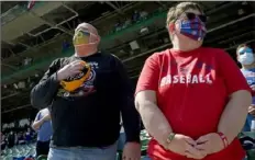  ??  ?? Tracy Cooper, of Freemont, Neb., left, stands for the national anthem with his wife, Diane. Mr. Cooper became a fan of the Pirates in the late 1960s and early ‘70s and has stuck with them ever since.