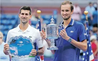  ?? USA TODAY Sports ?? NOVAK Djokovic, left, and Daniil Medvedev pose with the finalist and championsh­ip trophies, respective­ly, after their match in the men’s singles final of the US Open. | DANIELLE PARHIZKARA­N