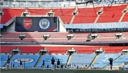  ??  ?? Empty feeling: The Arsenal and Manchester City players warm up before last season’s FA Cup semi-final in July 2020 at a deserted Wembley