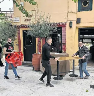  ?? PHOTO AFP ?? Des employés rentrent des tables à l’intérieur d’un restaurant situé dans le centre d’Athènes alors que les cafés, bars et restaurant­s ont fermé hier.