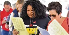  ?? HYOSUB SHIN / HSHIN@ AJC.COM ?? Kiara Ross (center) of Lawrencevi­lle fills out a voting form as she lines up for early voting at the Gwinnett County elections office.