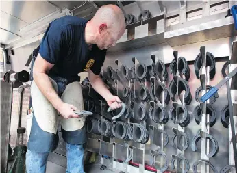  ??  ?? Farrier Thomas Nolan chooses from the assortment of shoes in the NYPD’s mobile workshop. The NYPD has two such mobile horseshoe units stocked with all manner of anvils, hammers, nippers and pullers.