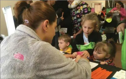  ?? ZACHARY SRNIS — THE MORNING JOURNAL ?? Jessica Justice, a sexual assault victim advocate for the Nord Center, front, traces the hand of Venessa Shaner, 2, of Oberlin, right, as Lily Wernette, 6, and Oliver Shaner, 3, both also from Oberlin, wait their turns.