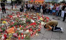  ?? PHOTO: REUTERS ?? A man prays beside flowers laid in front of the Olympia shopping mall, where Saturday’s shooting rampage started in Munich.