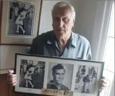  ?? Connie Grosch/Providence Journal via AP ?? In this July 2, 2009, photo, George Mendonsa holds a copy of the famous Alfred Eisenstaed­t photograph of Mr. Mendonsa kissing a woman in a nurse’s uniform in Times Square on Aug. 14, 1945, while celebratin­g the end of World War II.