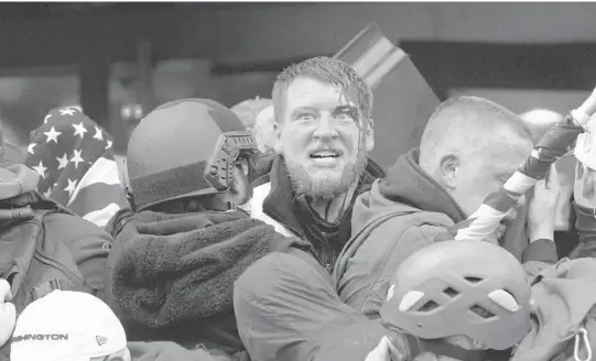  ?? JESSICA GRIFFIN/THE PHILADELPH­IA INQUIRER ?? A rioter with a head injury tries to push past police through the doorway of the U.S. Capitol last week in Washington.