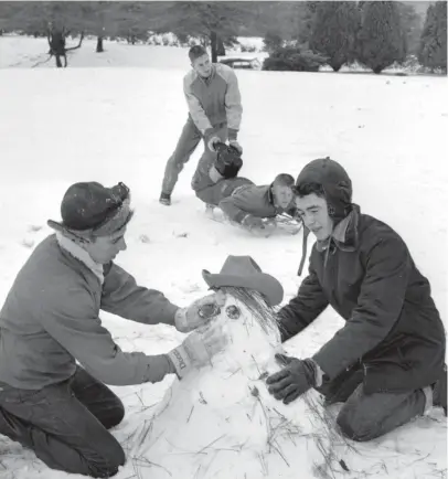  ?? THE COMMERCIAL APPEAL ?? The North wind did blow — and we did have snow on Jan. 22, 1954, sufficient for the masterpiec­e with pinecone eyes, at least. The artists are Bobby Ellis, left, and Fred Holland. The laborer in back is David Tillinghas­t, and the lucky sledder is Bruce Jones.