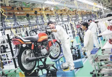  ??  ?? Employees work on an assembly line of Hero Motocorp during a media tour to the newly opened plant in Neemrana, in the desert Indian state of Rajasthan. — Reuters photo