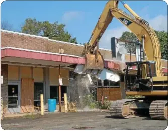  ??  ?? A demolition excavator takes the first chuck out of the building.