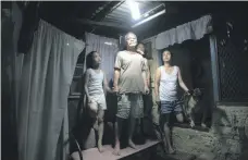  ?? EPA ?? In San Juan City, east of Manila, Simplicio Mondas, his daughter Olivia, right, with granddaugh­ter Maristela, left, and grandson Michael show their solar bottle bulb in their shanty