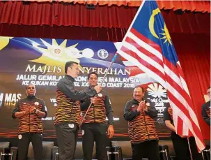  ?? — GLENN GUAN/ The Star ?? Make us proud: Chef-de-Mission Huang Ying How (second from left) receiving the Jalur Gemilang from Youth and Sports Minister Khairy Jamaluddin (second from right) during the flag handing ceremony for the Gold Coast Commonweal­th Games yesterday. Top...