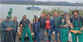  ?? ?? Role players at Groenvlei, where the carp are being caught. BELOW: Gift of the Givers’ Southern Cape coordinato­r Mario Ferreira (left) hands out fish to the community.