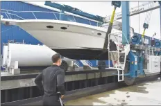  ?? Alexander Soule / Hearst Connecticu­t Media ?? As Terry Murphy looks on, Peter Manion lowers the Murphy family’s power boat Running Bear into Stamford Harbor on Wednesday at Hinckley’s new boatyard on Selleck Street.