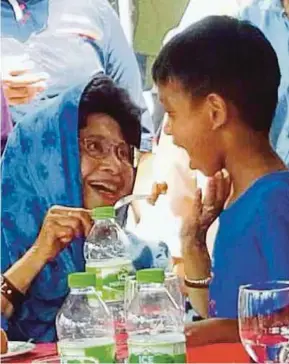  ?? (Foto Hamzah Osman/bh) ?? Dr Siti Hasmah menyuapkan sepotong kuih kepada Adam Mustaqim pada Majlis Korban Masjid Ar Rahman Kampung Kedawang, Langkawi, semalam.