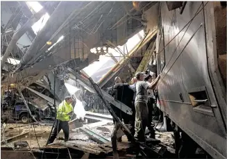  ?? PANCHO BERNASCONI / GETTY IMAGES ?? Train personnel survey the New Jersey Transit train that crashed through a concrete-and-steel bumper and ground to a halt in a waiting area at the Hoboken station on Thursday morning. A 34-year-old woman standing on the platform was killed by debris,...