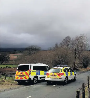  ??  ?? > Police man a roadblock in Trawsfynyd­d, north Wales, where the wreckage has been discovered of a Twin Squirrel helicopter. Inset: The air exclusion zone around the Rhinog area