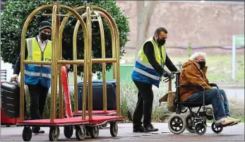  ??  ?? Happy landing: a passenger from Heathrow is wheeled into a nearby hotel for quarantine today