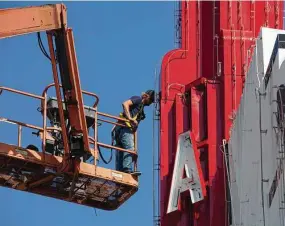  ??  ?? Yi-Chin Lee / Staff photograph­er
Technician Tre Fairburn works on the installati­on of the updated neon signs on the tower of the new Acme Oyster House.